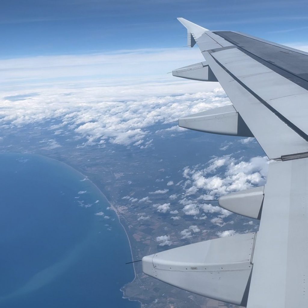 looking out over the airplane wing to see the ocean and land below